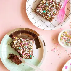 Deliciosos trozos de pastel de chocolate con chispas de colores y estrellas, listos para una merienda de cumpleaños infantil.