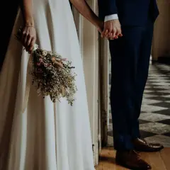 Novios tomados de la mano, ella con un ramo de flores secas, listos para su ceremonia civil.