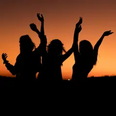 Siluetas de tres amigas bailando al atardecer. Los planes con amigas son los mejores.