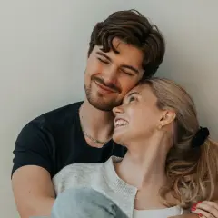 Una pareja joven se abraza tiernamente, sus rostros iluminados por una sonrisa que refleja el amor verdadero.