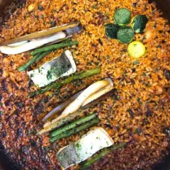 Paella con mariscos, espárragos y pescado. El fondo dorado y crujiente es el socarrat que es la parte más sabrosa.