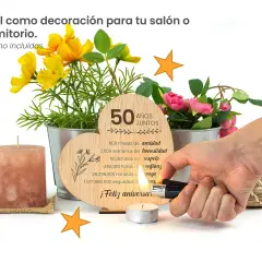 Corazón de madera con "50 Años Juntos" y detalles de flores. Un encendedor ilumina una vela, celebrando un feliz aniversario 50 años de casados.