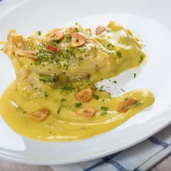 Bacalao en salsa pil pil, con láminas de ajo crujiente y perejil picado. Una deliciosa receta para disfrutar.