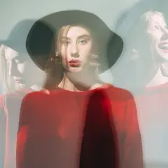 Mujer con sombrero y suéter rojo, capturada en múltiples exposiciones, reflejando su labilidad emocional.