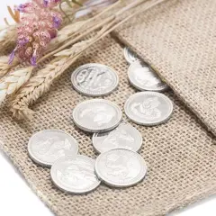Monedas plateadas, símbolo de prosperidad, junto a espigas y flores secas, representando las arras de boda.