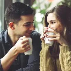 Una pareja joven comparte un café, mirándose con ternura. Un momento perfecto para pensar como decirle a alguien que te gusta.
