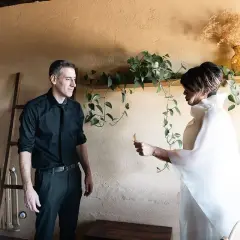 Pareja intercambiando un detalle, quizás una nota, como parte de sus ideas para aniversario. Él, de negro; ella, de blanco.