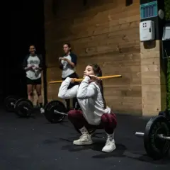 Mujeres entrenando en un gimnasio, demostrando los beneficios del crossfit con una barra.