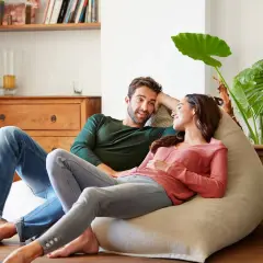 Parejas lat relajadas en un puf, compartiendo un momento íntimo en casa.
