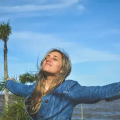 Mujer con brazos extendidos, disfrutando del aire libre, como si viviera una de las frases de Lao Tse sobre la libertad y la naturaleza.