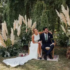 Novios sonriendo en su **boda del año**, rodeados de pampas y vegetación exuberante.