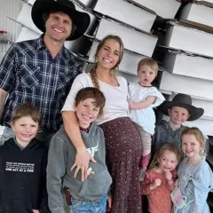 Familia feliz, estilo tradwife que es, posando con sus hijos frente a cajas apiladas.