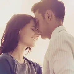 Parejas enamoradas, con sus frentes juntas y sonrisas tiernas, bajo la luz cálida del atardecer.