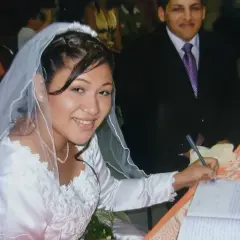 Novia sonriente firma su acta de matrimonio. A su lado, el novio. Celebrando 17 años de casados.