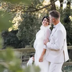 Pareja sonriente en su segunda boda a los 50 años de edad. Ella luce un vestido blanco vaporoso, él un traje claro.