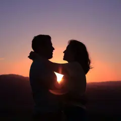 Siluetas de pareja abrazándose al atardecer. Su conexión irradia una profunda compatibilidad, como si fueran cáncer y cáncer, unidos por el amor.