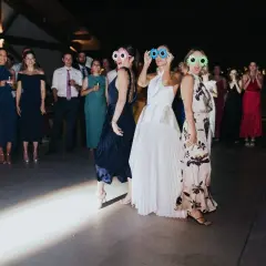Un grupo de mujeres con gafas divertidas celebra una sorpresa para los novios en una fiesta.