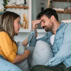 Mujer consuela a su pareja, con la mano en su frente, en un momento de tensión en su vida en pareja.