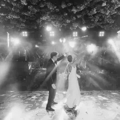 Novios bailando su primera canción, rodeados de luces y vegetación exuberante. La pista de baile decorada con un patrón intrincado.