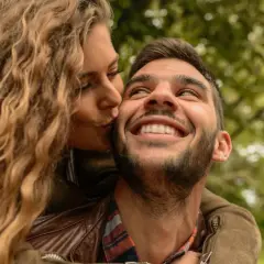 Una mujer rubia besa en la mejilla a un hombre sonriente. Las reglas de pareja se basan en el amor y la confianza.