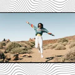 Una joven salta de alegría en un paisaje árido, un momento capturado que inspira frases de felicidad.