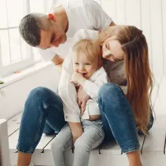 Padres abrazando a su hijo, creando un ambiente de apego seguro. El niño sonríe, rodeado de amor y protección.