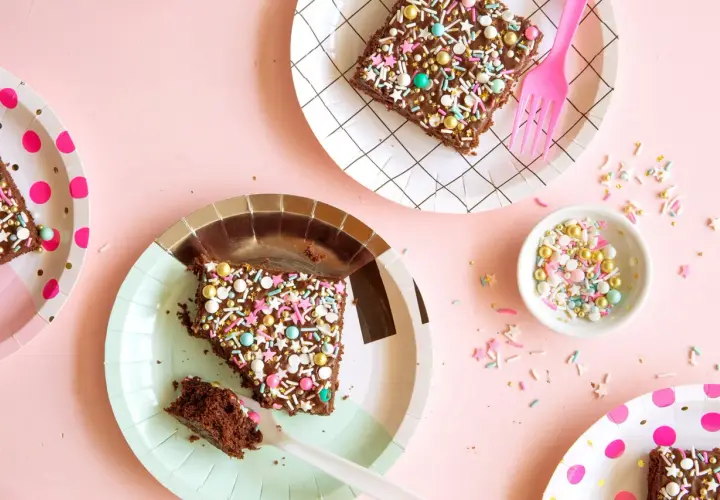 Deliciosos trozos de pastel de chocolate con chispas de colores y estrellas, listos para una merienda de cumpleaños infantil.