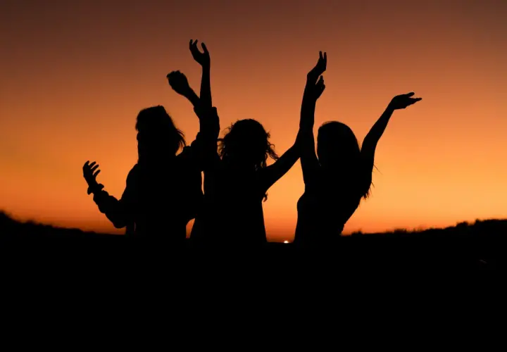 Siluetas de tres amigas bailando al atardecer. Los planes con amigas son los mejores.