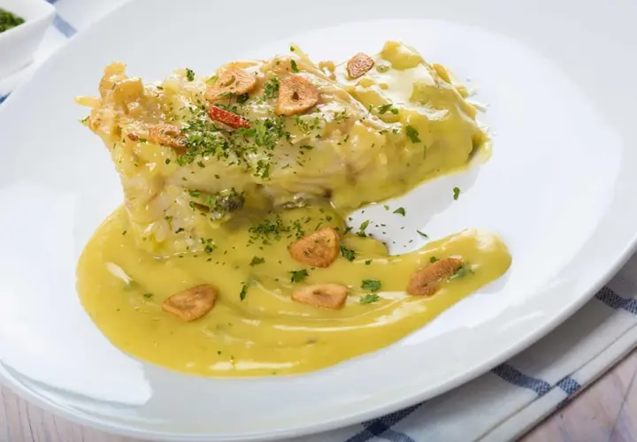 Bacalao en salsa pil pil, con láminas de ajo crujiente y perejil picado. Una deliciosa receta para disfrutar.