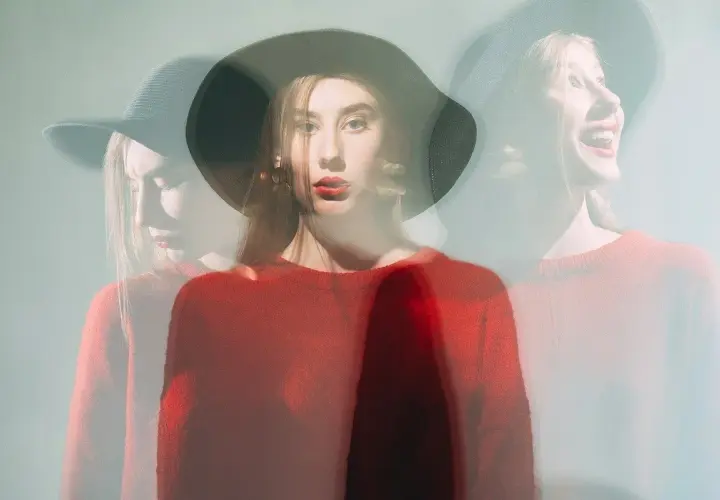 Mujer con sombrero y suéter rojo, capturada en múltiples exposiciones, reflejando su labilidad emocional.