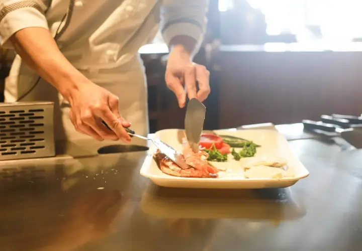 Chef emplata camarones y vegetales. El arte del show cooking, el significado de la pasión culinaria.