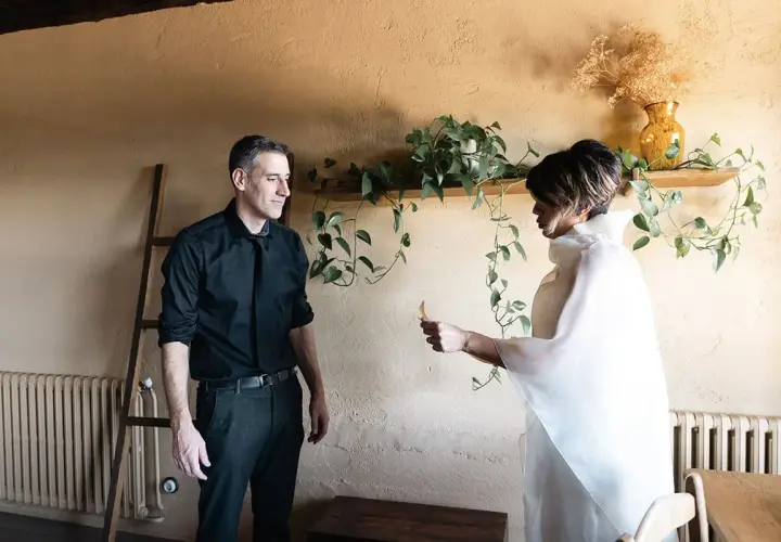 Pareja intercambiando un detalle, quizás una nota, como parte de sus ideas para aniversario. Él, de negro; ella, de blanco.