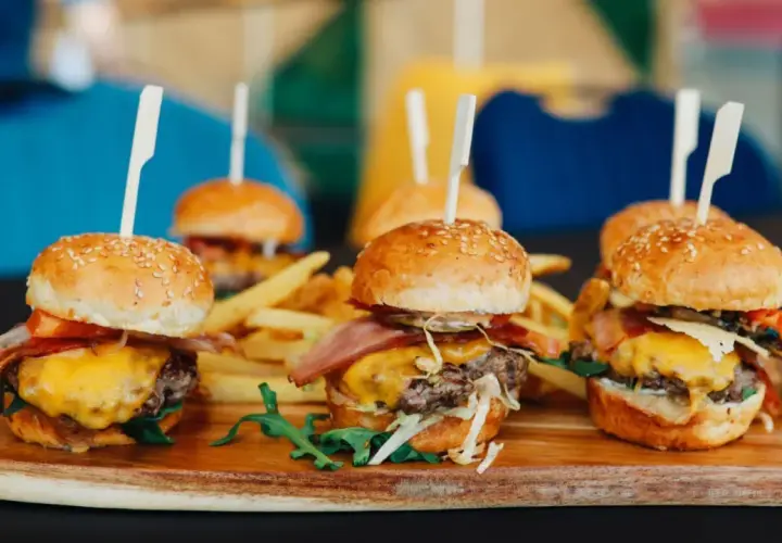 Picoteo comida para cumpleaños en casa: mini hamburguesas jugosas con queso fundido, tocino crujiente y papas fritas. ¡Un festín delicioso!