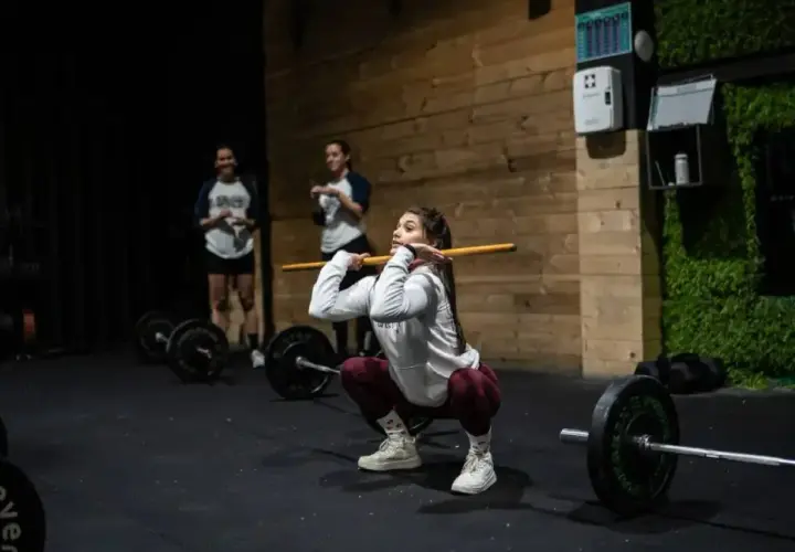 Mujeres entrenando en un gimnasio, demostrando los beneficios del crossfit con una barra.