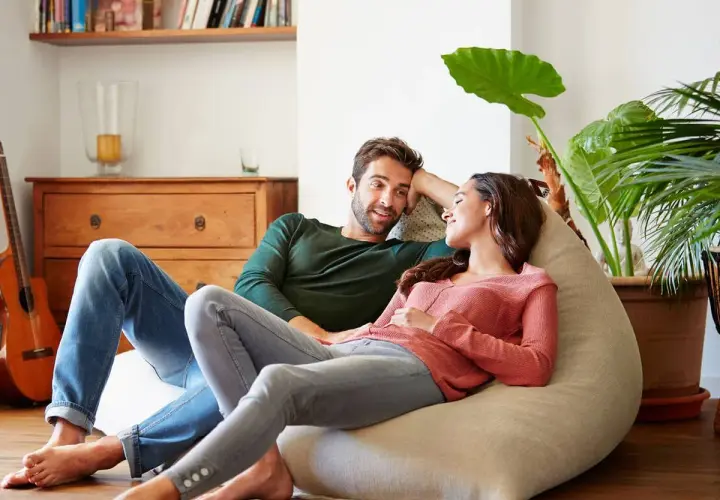 Parejas lat relajadas en un puf, compartiendo un momento íntimo en casa.