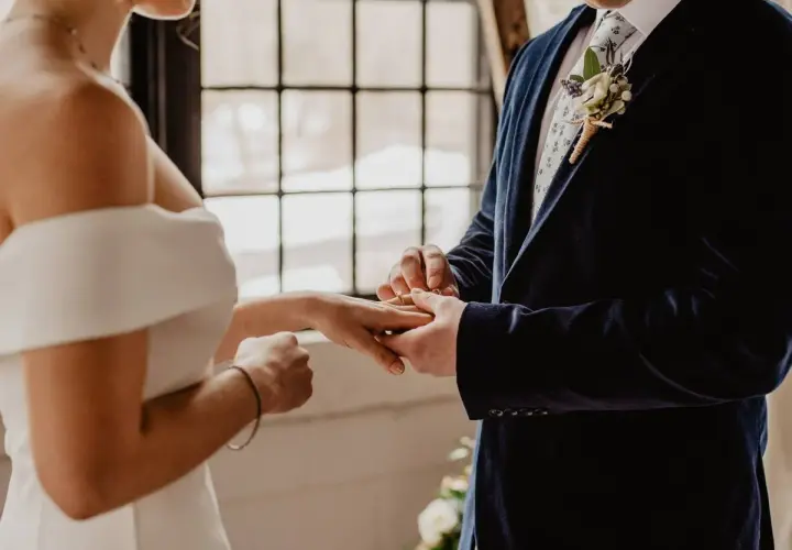 Novio pone anillo a novia. Un juez o funcionario civil es quien puede oficiar una boda civil.