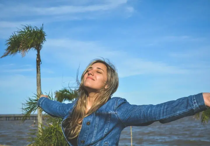 Mujer con brazos extendidos, disfrutando del aire libre, como si viviera una de las frases de Lao Tse sobre la libertad y la naturaleza.