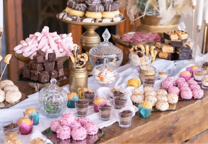 Mesa dulce casera para boda: brownies, malvaviscos rosas, donuts, pastelitos y más.
