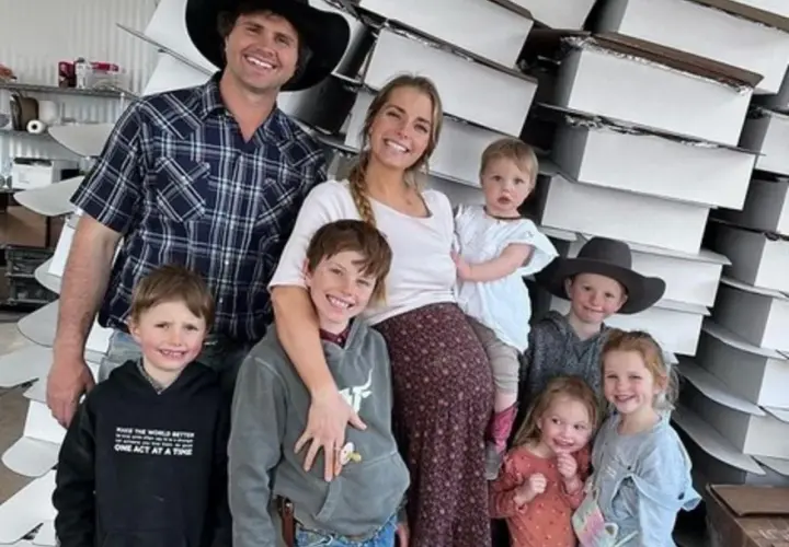 Familia feliz, estilo tradwife que es, posando con sus hijos frente a cajas apiladas.