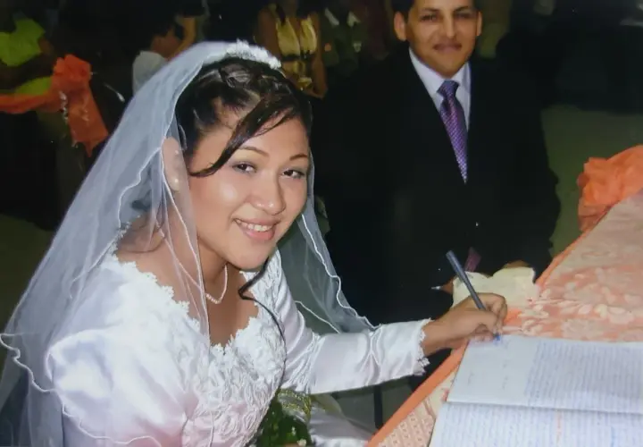 Novia sonriente firma su acta de matrimonio. A su lado, el novio. Celebrando 17 años de casados.