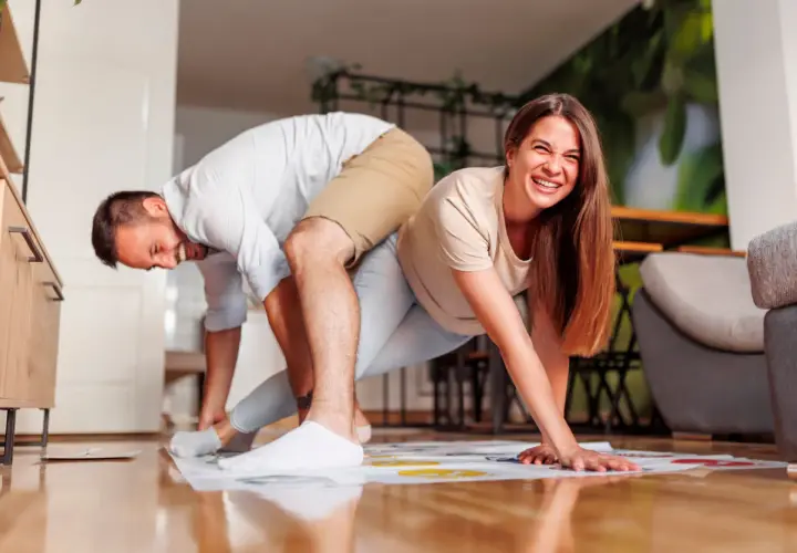 Pareja riendo mientras juega Twister, un divertido juego para jugar en pareja.