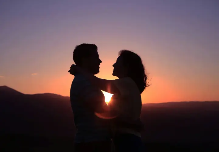 Siluetas de pareja abrazándose al atardecer. Su conexión irradia una profunda compatibilidad, como si fueran cáncer y cáncer, unidos por el amor.