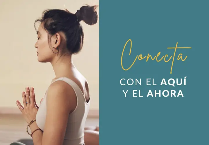 Mujer meditando con las manos juntas, practicando mindfulness ejercicios para conectar con el aquí y el ahora.