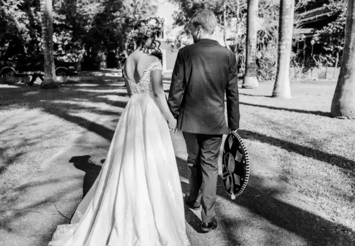 Novios caminando de la mano, ella con vestido de novia y él con traje y sombrero charro. Un recuerdo para todos los nombres de aniversarios de boda.