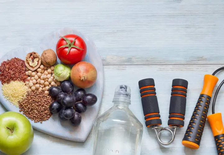 Alimentos saludables y equipo de ejercicio, como una cuerda de saltar y un expansor de mano, para tu motivación personal.