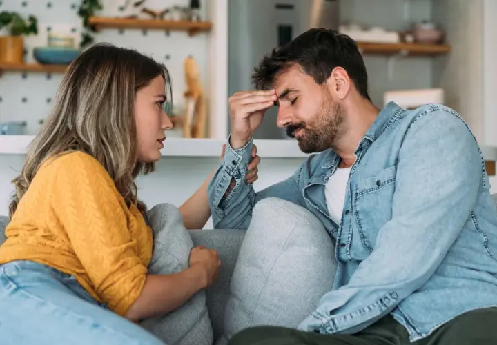 Mujer consuela a su pareja, con la mano en su frente, en un momento de tensión en su vida en pareja.