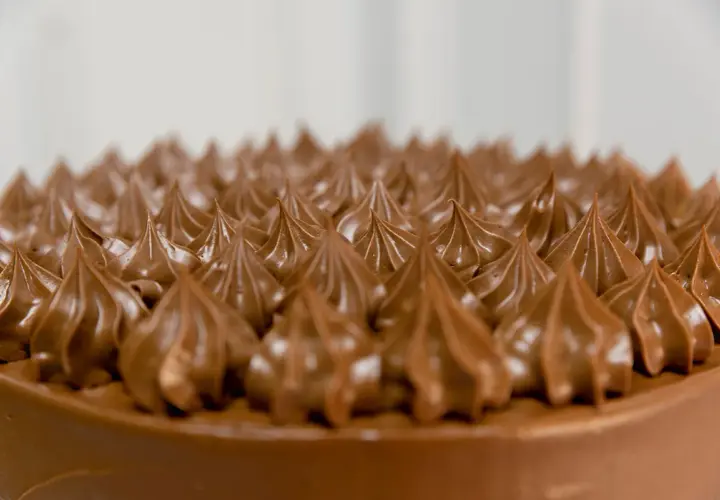 Detalle de una tarta de chocolate con glaseado cremoso, evocando deliciosos sabores de tarta.