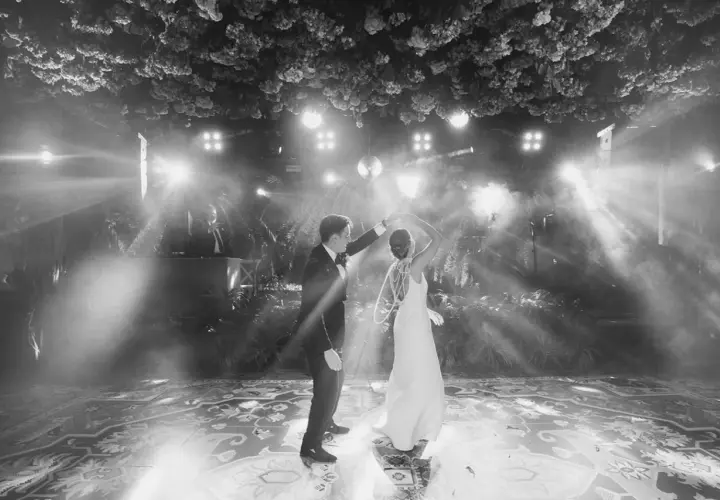 Novios bailando su primera canción, rodeados de luces y vegetación exuberante. La pista de baile decorada con un patrón intrincado.