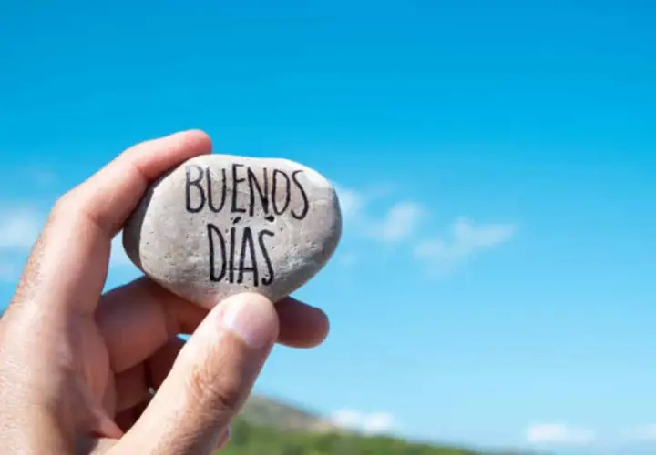 Un cariñoso saludo de buenos días alegres, escrito en una piedra sostenida contra un cielo azul brillante.