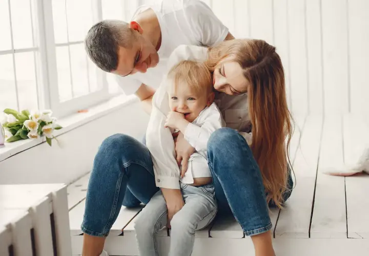 Padres abrazando a su hijo, creando un ambiente de apego seguro. El niño sonríe, rodeado de amor y protección.